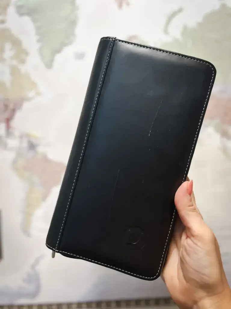 25-of-the-best-travel-essentials-from-Amazon - Sweet Motherly A person holding a black leather wallet in front of a map.