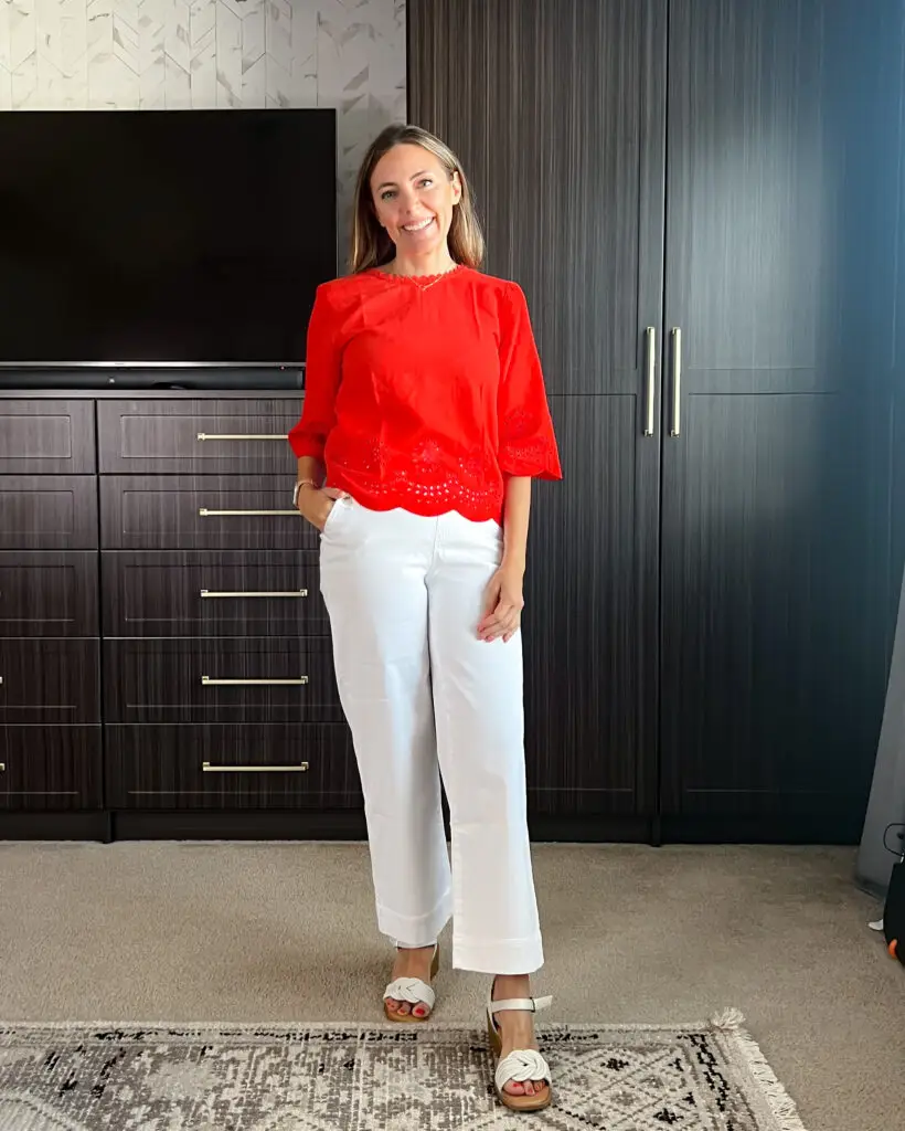 A woman standing in front of a closet wearing white pants.