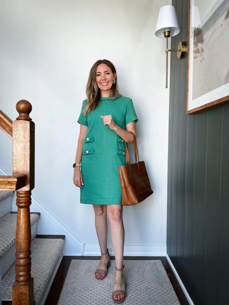 A woman standing on the stairs wearing a green dress.
