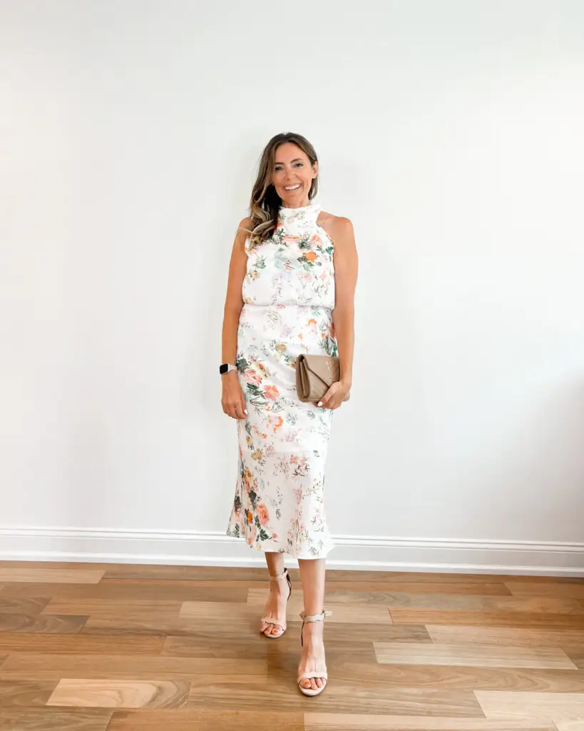 A woman standing in front of a wall holding onto a purse.