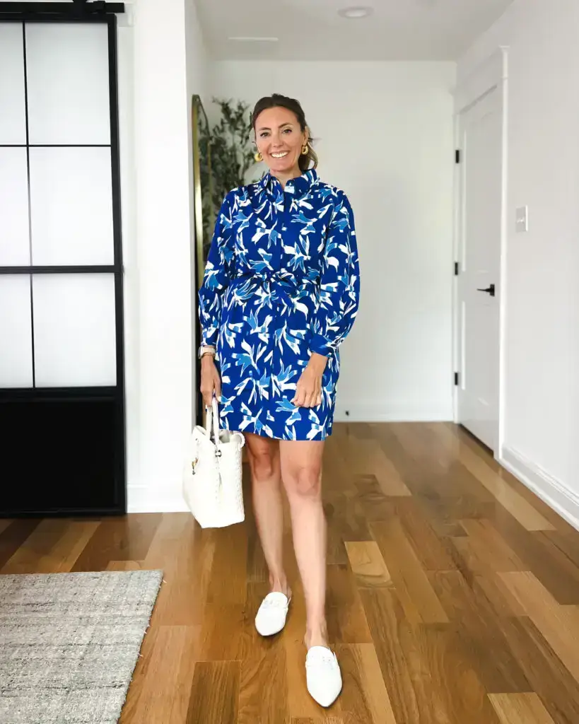 A woman standing in front of a door wearing a blue dress.