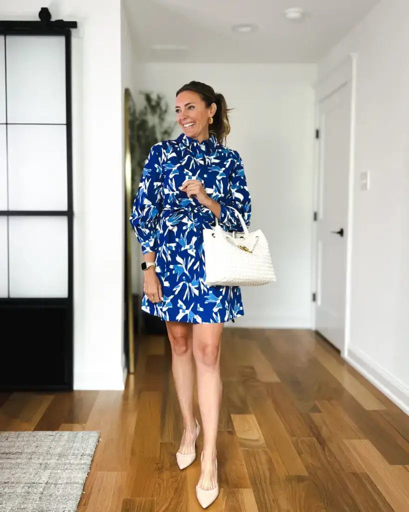 A woman in blue and white dress holding a purse.