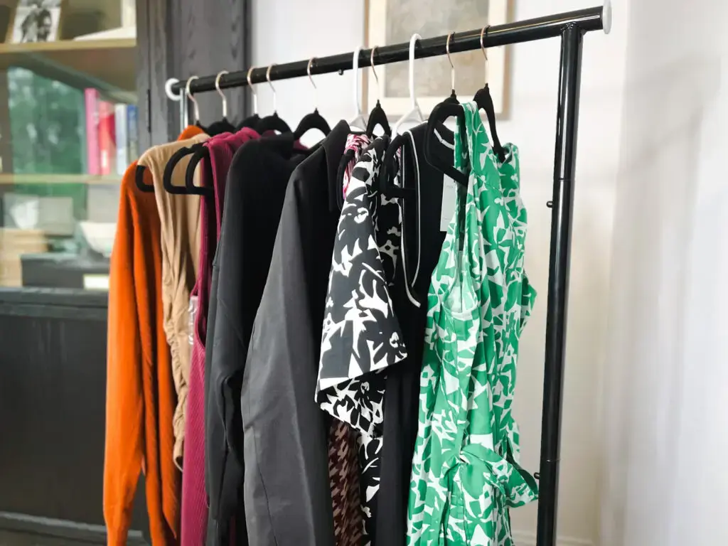 A rack of clothes hanging on the side of a window.