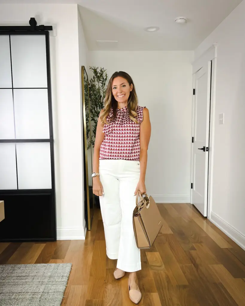 A woman standing in front of a door wearing white pants.