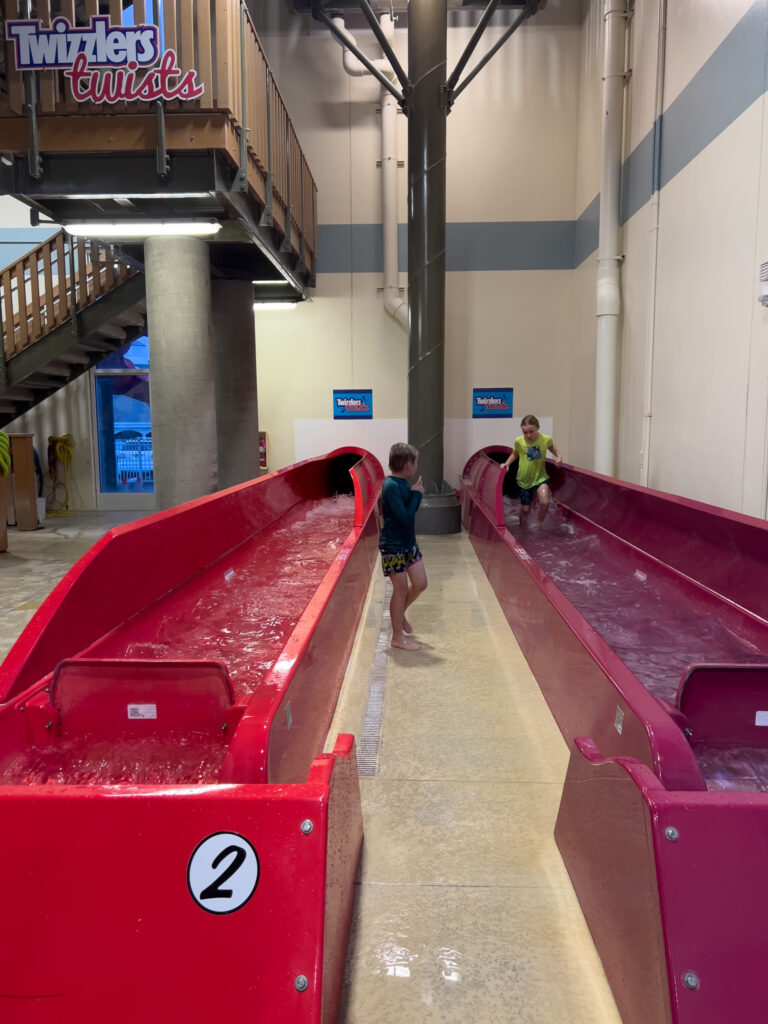 Two people are standing in a building with some water slides.