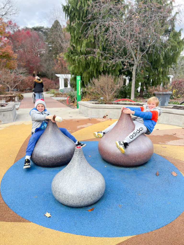 Two children are playing on a toy in the park.