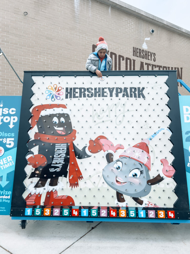 A person standing next to a hershey park sign.