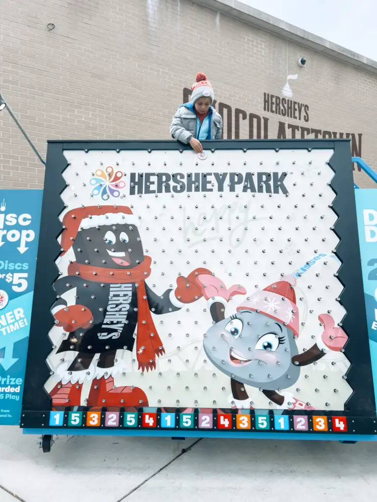 The-Ultimate-Weekend-in-Hershey-Holiday-Getaway-Guide - Sweet Motherly A person standing next to a hershey park sign.