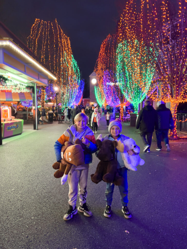 Two children holding stuffed animals in a park.