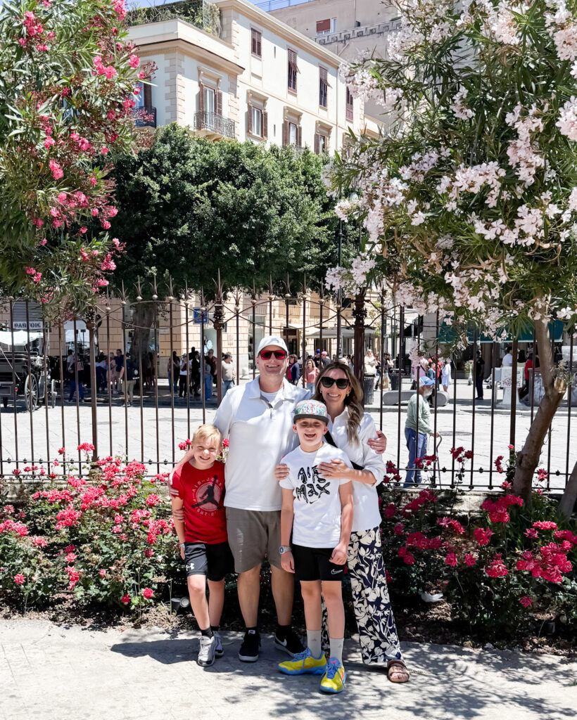 Family Smiling in Palermo City Center with Spring Blooms - Sweet Motherly Family of four smiling in front of blooming flowers and buildings in downtown Palermo, Sicily.