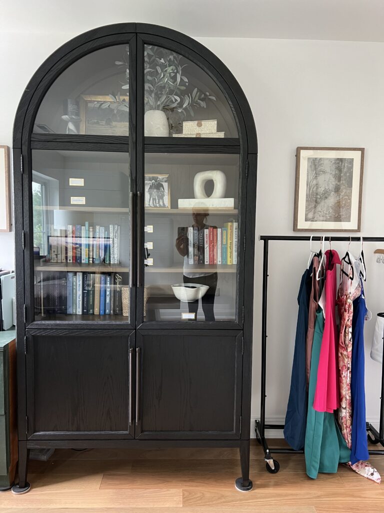 Black arched Arhaus cabinet styled with books and props in a modern home office setup