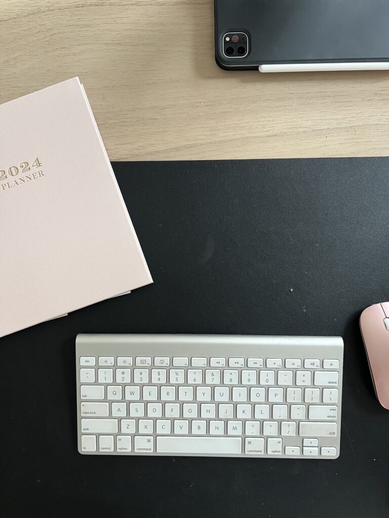 Minimal home office desk setup with sculptural CB2 desk, blush planner, and Amazon desk mat