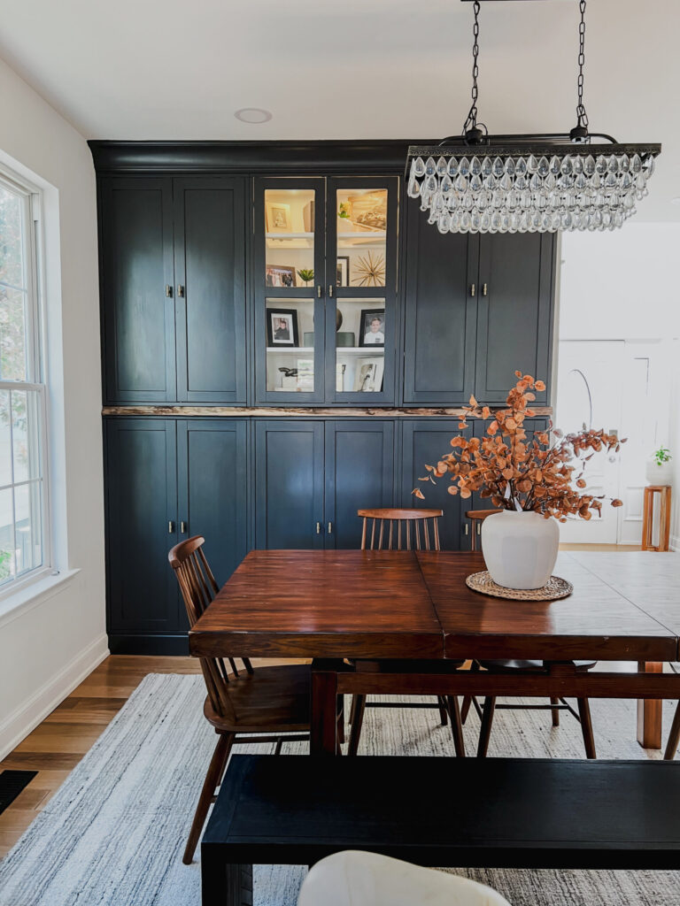 Ikea Havsta cabinet makeover painted in Benjamin Moore Iron Ore with crystal chandelier and wood dining table, a dramatic storage hack idea.