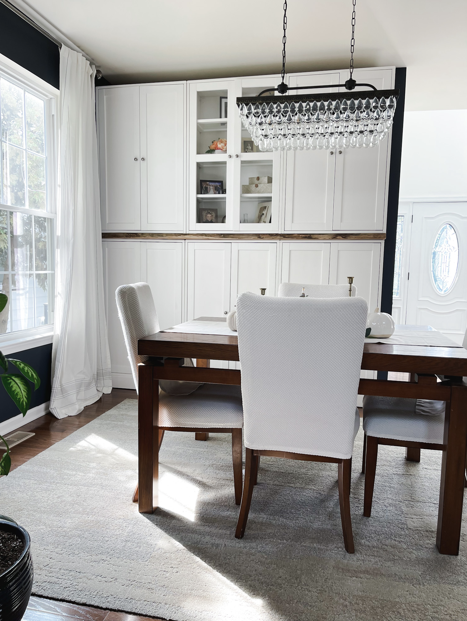 Crisp white Ikea cabinets paired with a wood dining table and upholstered chairs, an affordable built-in storage hack.