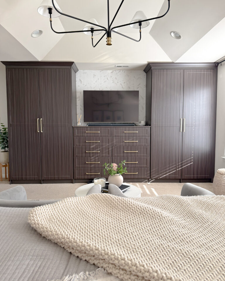 A view of the custom dark wood cabinetry framing the TV wall, brass hardware details, and a modern black chandelier overhead.