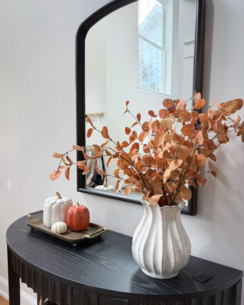 IMG_4351 - Sweet Motherly Fall entryway styling with black console table, white vase of dried leaves, and gold tray with pumpkins
