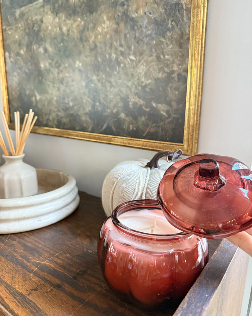 IMG_4369 - Sweet Motherly Warm-toned fall vignette with framed art, red glass jar, and ceramic bowl on wooden table