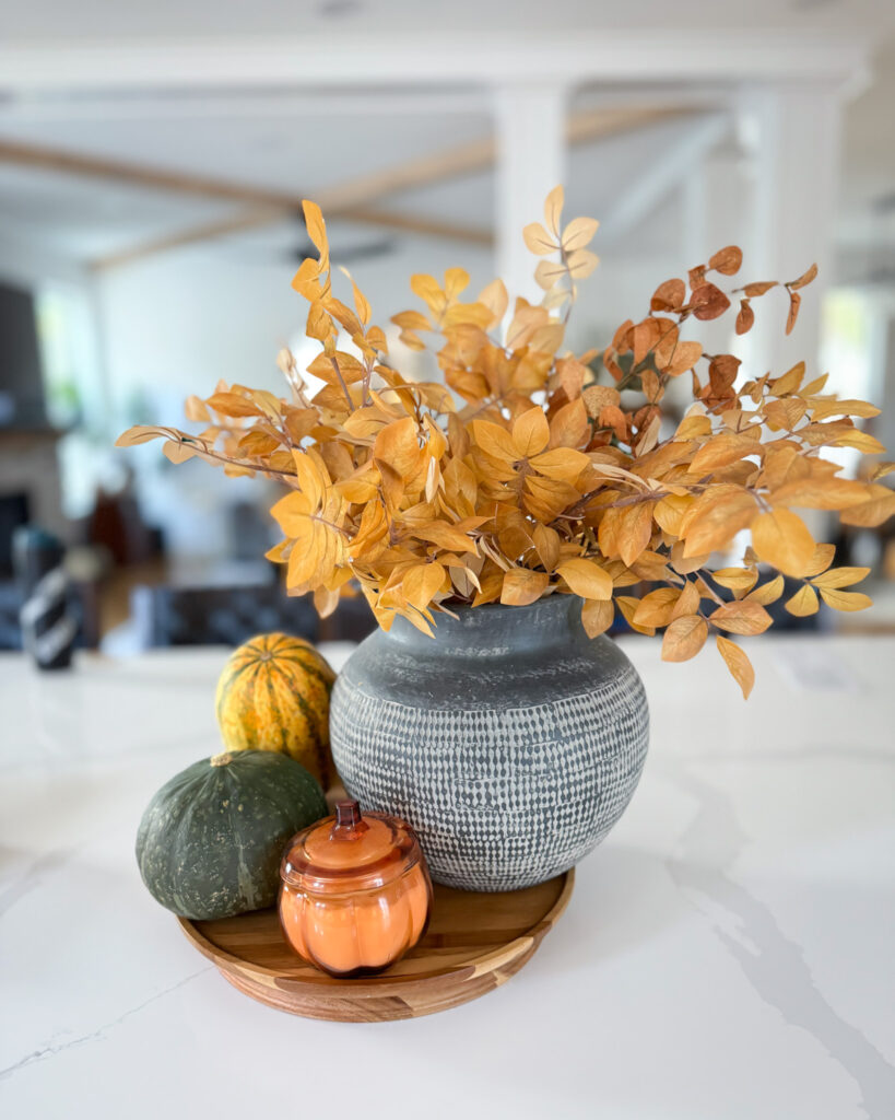 IMG_4377 - Sweet Motherly Neutral fall vignette with gray vase of yellow stems, small pumpkins, and wood bowl on kitchen counter