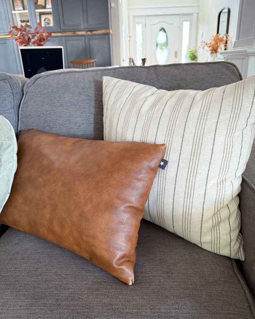 IMG_4417 - Sweet Motherly Gray couch styled with brown leather pillow and neutral striped cushion for cozy fall decor