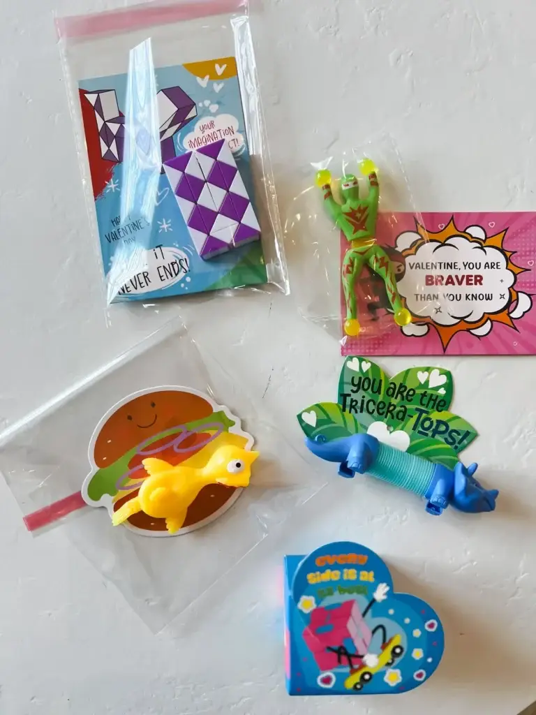 Valentine’s Day classroom favors including a snake puzzle, stretchy toy, mini card, and heart-shaped message displayed on a white background.