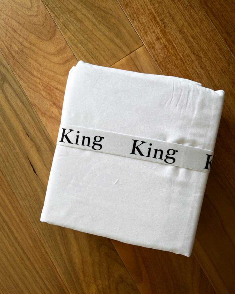 Linen closet shelf with folded sheet sets stored inside a sheet organizer.