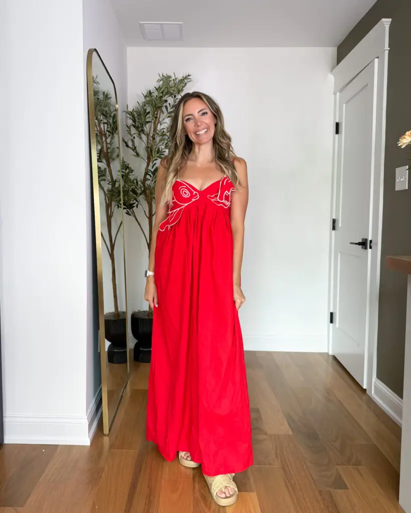 IMG_0915 1 - Sweet Motherly Woman wearing a bright red embroidered maxi dress with woven platform sandals, styled for a warm-weather vacation look in a neutral hallway setting.