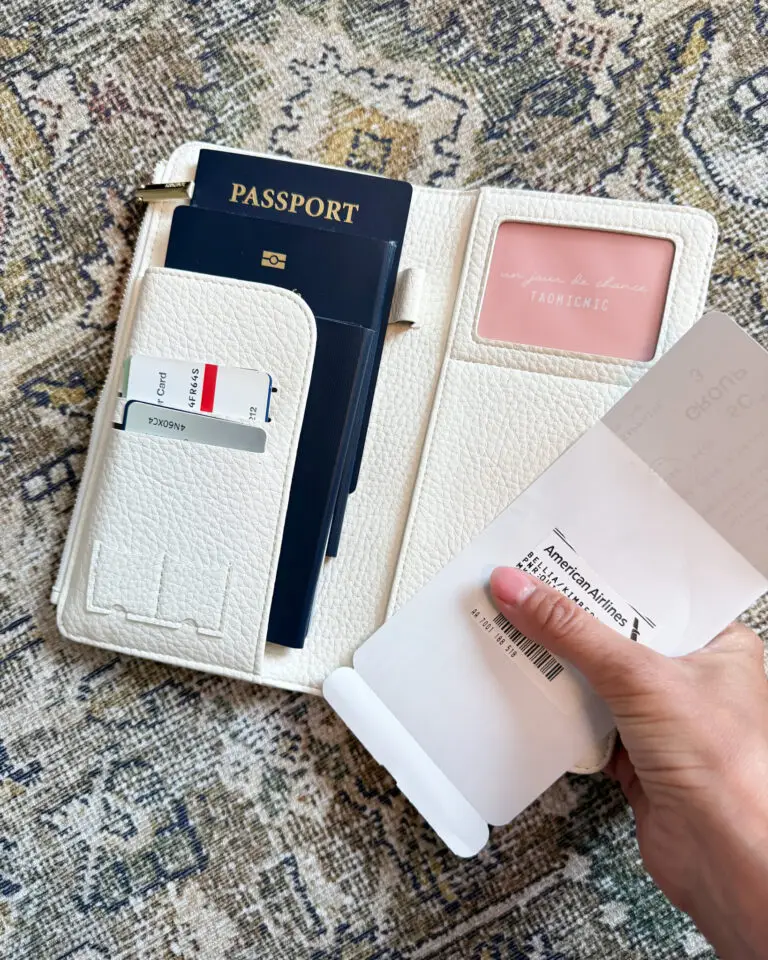 Cream travel wallet holding passport, credit cards, and boarding pass – organized Cruise Essentials from Amazon for embarkation day.
