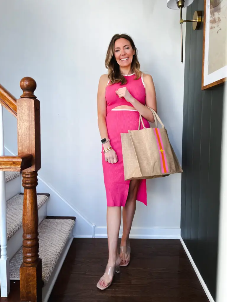 IMG_4753 - Sweet Motherly Woman wearing a bright pink ribbed crop top and midi skirt set with clear heels and a striped jute tote, styled as bold affordable resort wear for summer getaways.