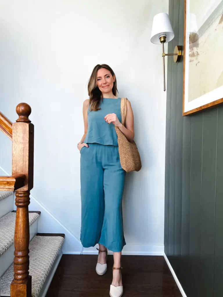 IMG_4843 - Sweet Motherly Woman in a teal sleeveless wide-leg jumpsuit styled with neutral mules and a woven shoulder bag, perfect for elevated vacation dinners or casual resort evenings.
