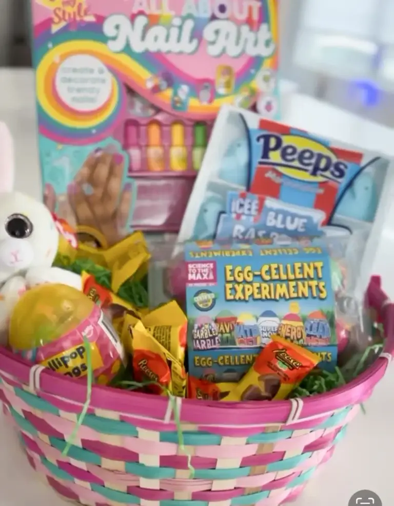 Pink and teal woven Easter basket filled with kids Easter basket stuffers including Peeps marshmallows, Reese’s candy, Lollipop Rings candy, Egg-Cellent Experiments kit, All About Nail Art set, plush bunny, and colorful Easter treats.