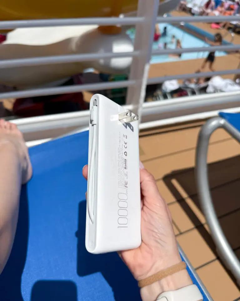 IMG_8766-768x960 - Sweet Motherly White portable power bank with built-in cables held on cruise ship balcony – practical Cruise Essentials from Amazon for staying charged at sea.