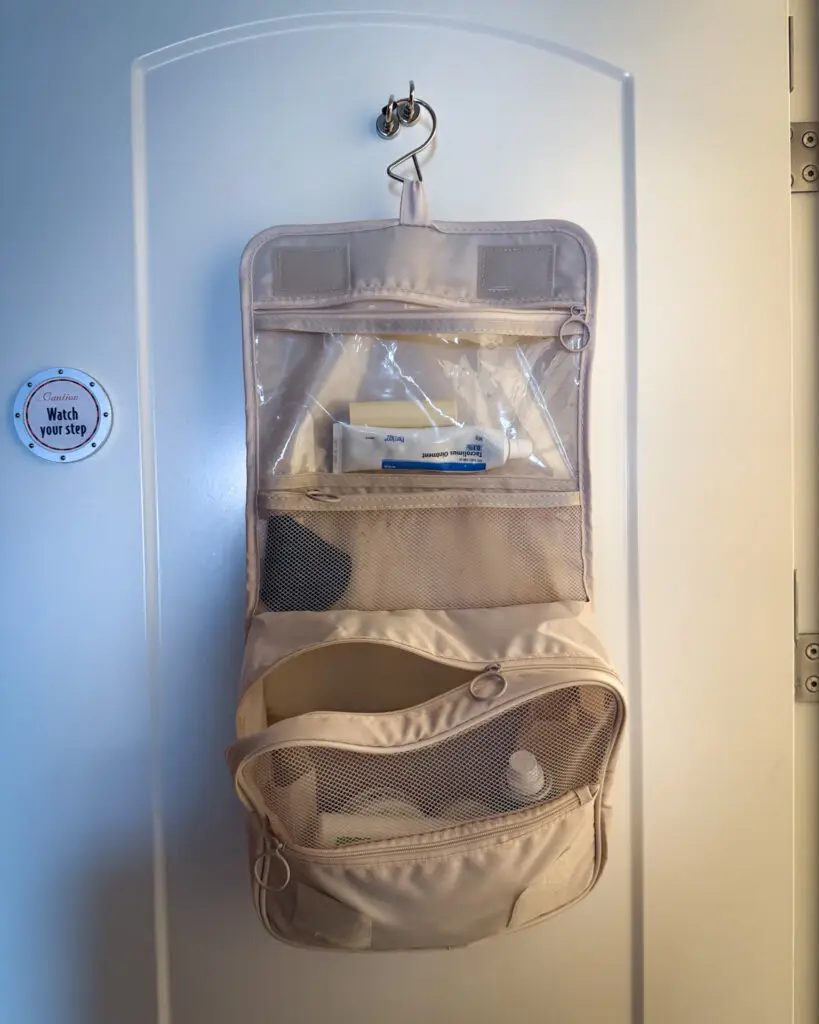 IMG_9282 - Sweet Motherly Neutral hanging toiletry organizer attached to cruise cabin wall hook with clear and mesh compartments – smart Cruise Essentials from Amazon for maximizing small bathroom space.