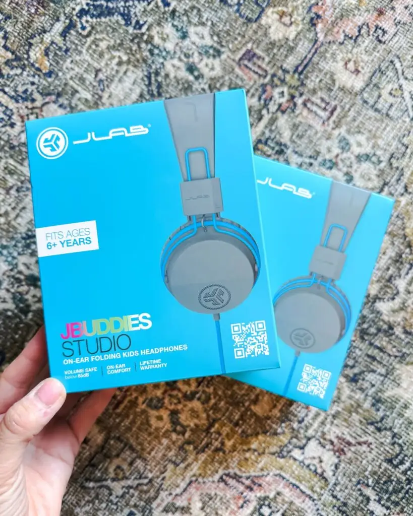 JLab JBuddies Studio kids headphones in blue packaging designed for safe volume listening, a top family travel essential from Amazon for flights.