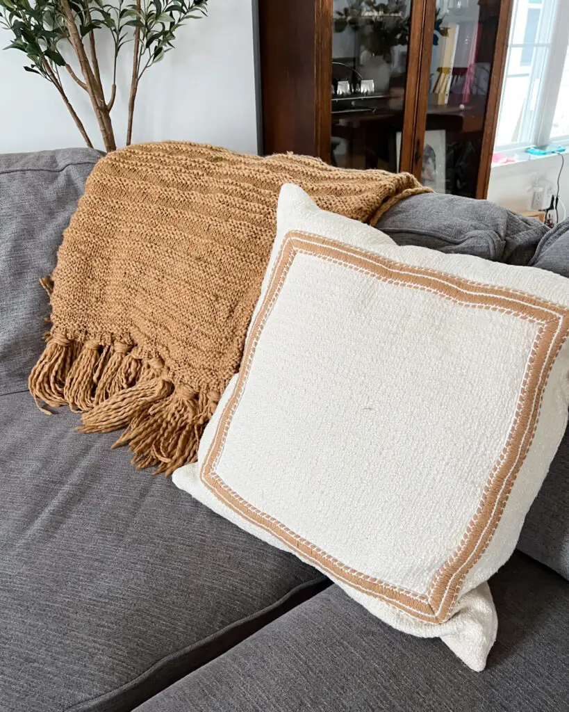 Neutral sofa styled with round crochet pillow and green floral lumbar pillow