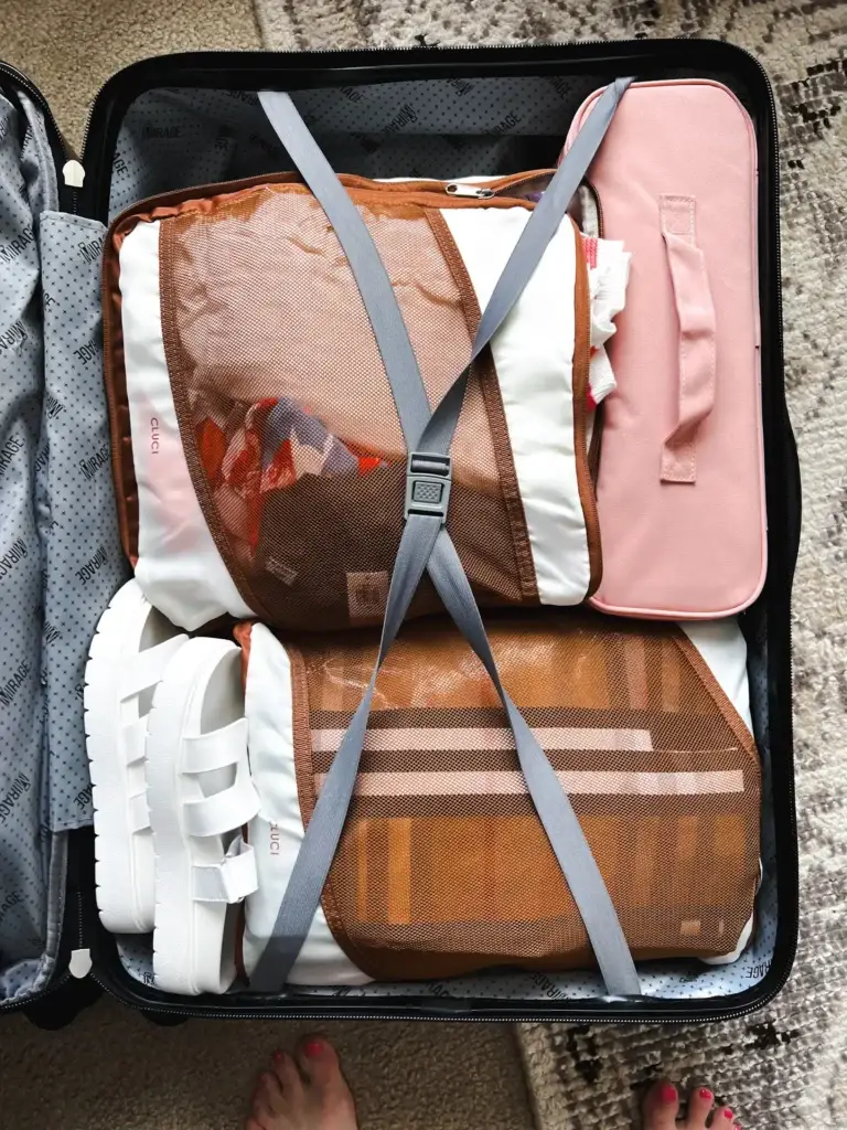 Open suitcase neatly packed with packing cubes, white sneakers, and organizers, showcasing family travel essentials from Amazon for stress-free packing.