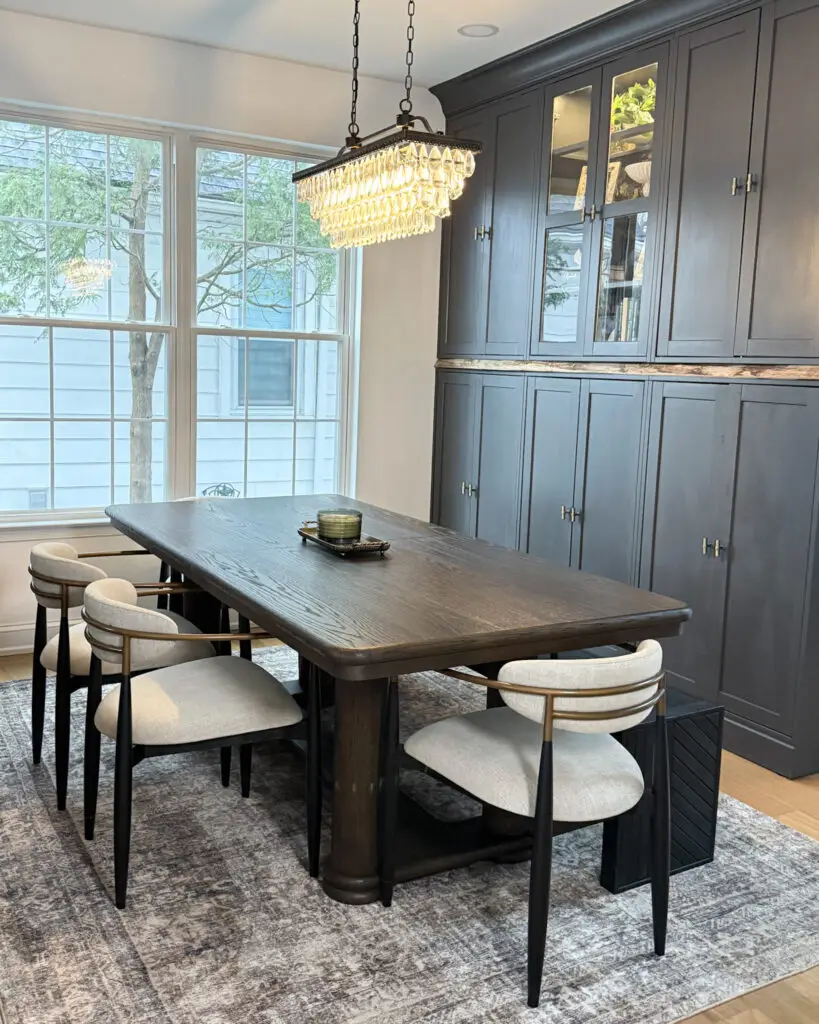 Modern dining room with dark wood table, upholstered chairs, and statement crystal chandelier