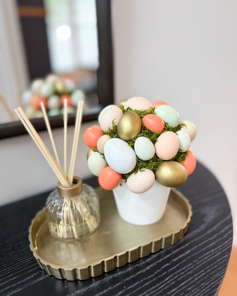 Small Easter egg topiary centerpiece with pastel eggs and moss on a gold tray with reed diffuser