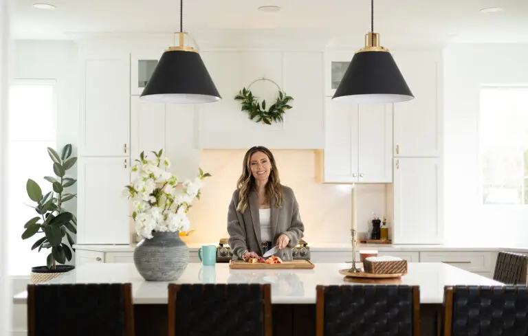 Bright white kitchen with large island, black pendant lights, and fresh florals styled in a vase