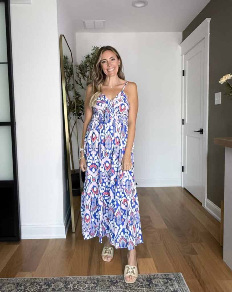 Screenshot 2026-05-28 at 31611 PM - Sweet Motherly Smiling woman standing in a modern foyer wearing a blue, white, and red patterned maxi dress.