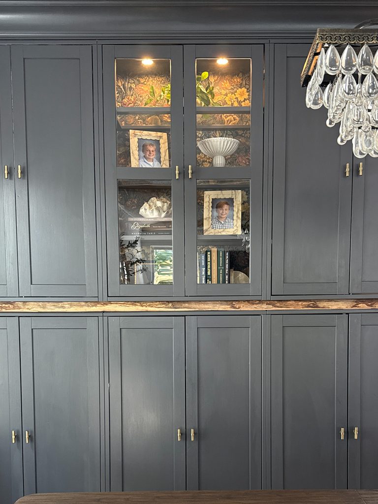 Lit IKEA Havsta glass-door cabinet lined with wall covering against Iron Ore paint