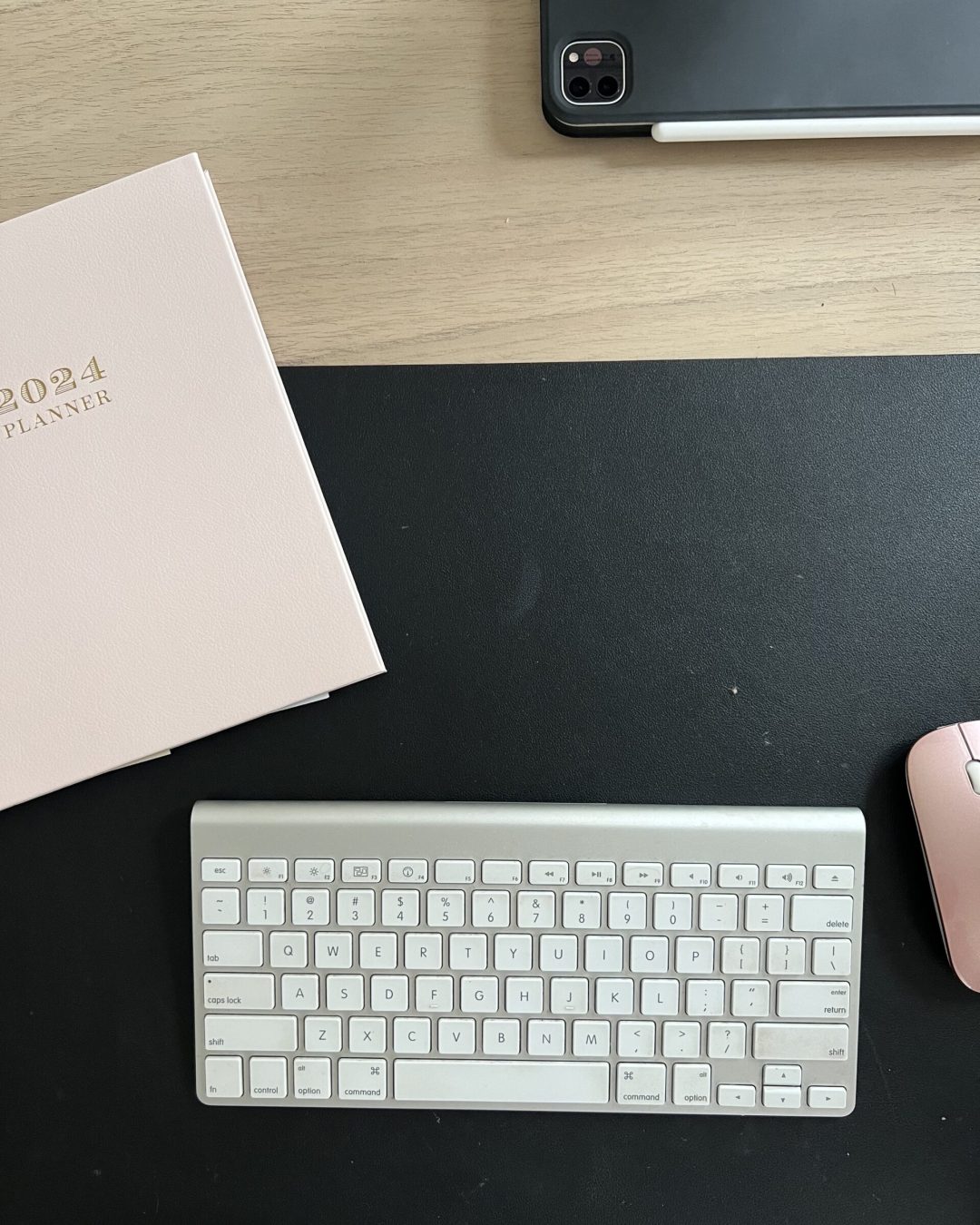 Minimal home office desk setup with sculptural CB2 desk, blush planner, and Amazon desk mat