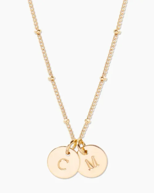 A gold necklace with two small discs and one of the same type of letter.
